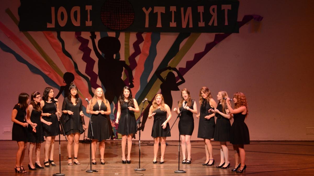 11名身穿黑色礼服的女歌手在舞台上为“赌博娱乐平台网址大全偶像”表演.